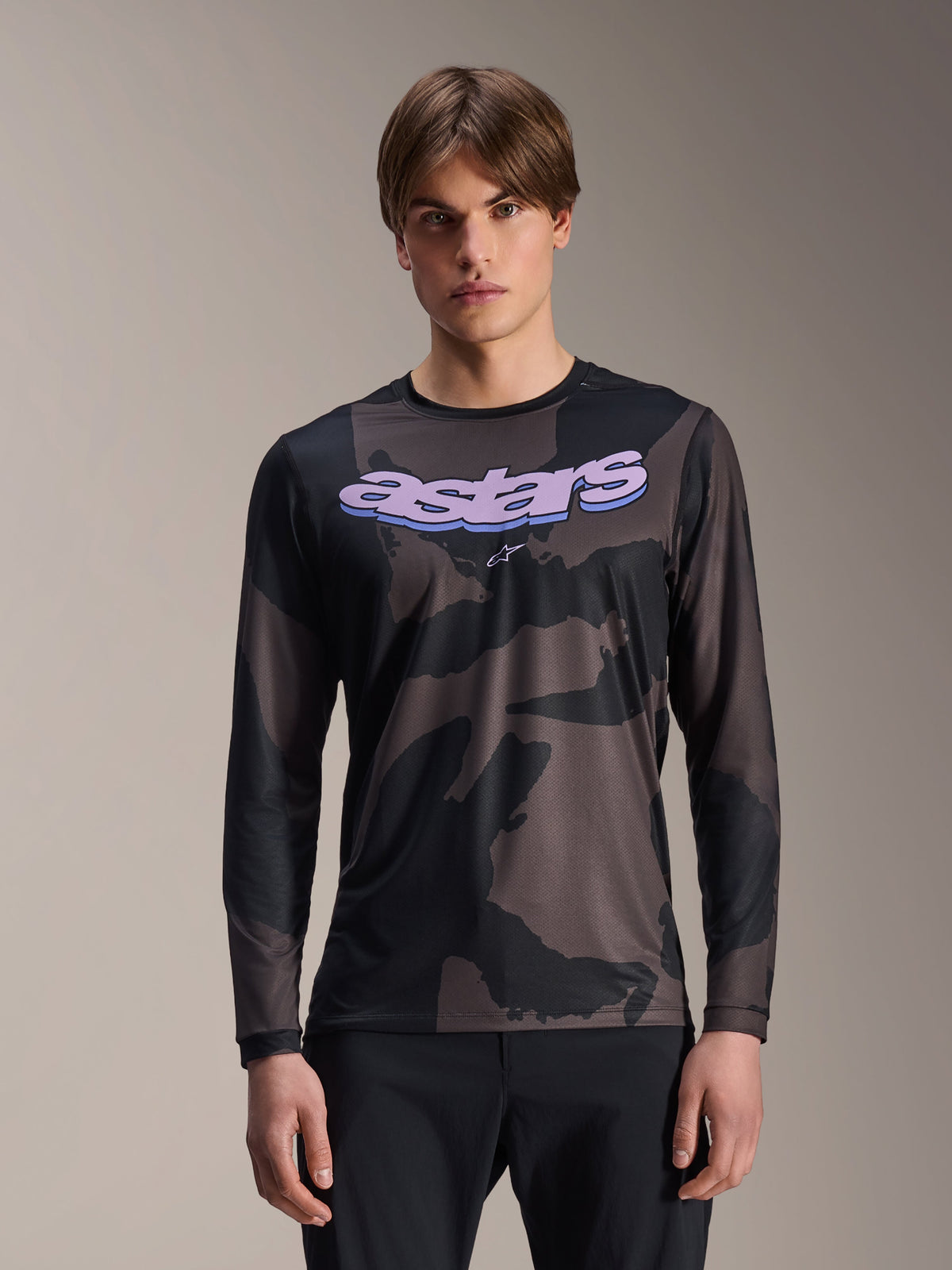 Alpinestars A-Dura Hollow Camo Long Sleeve Jersey, maillot de VTT, motif camouflage noir et gris, graphisme 'astars' violet sur la poitrine, porté par un mannequin avec un pantalon noir, design technique décontracté