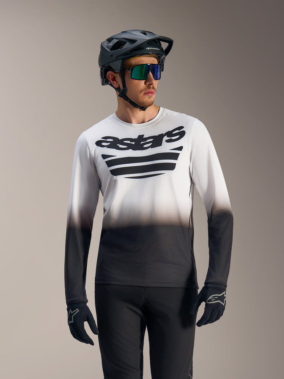 Maillot A-Dura ASTARS 2.0 manches longues, dégradé blanc et noir avec logo poitrine, porté avec équipement de VTT.