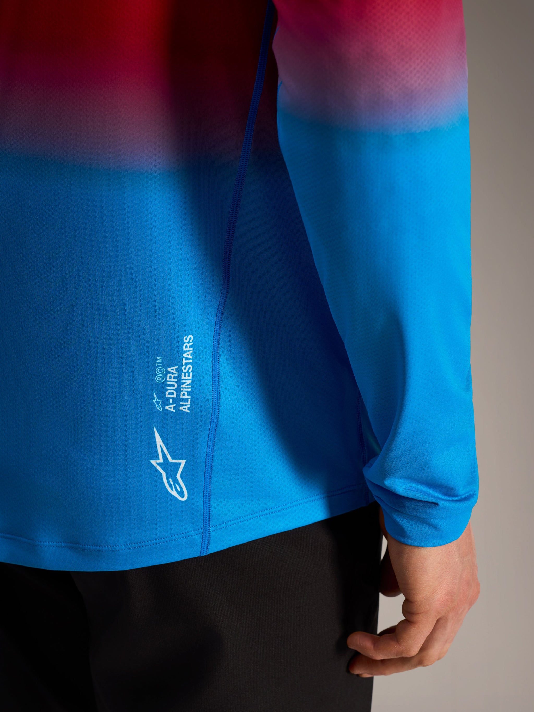 A-Dura ASTARS Long Sleeve Jersey 2.0 in red and blue gradient with white Alpinestars logo branding on the side.