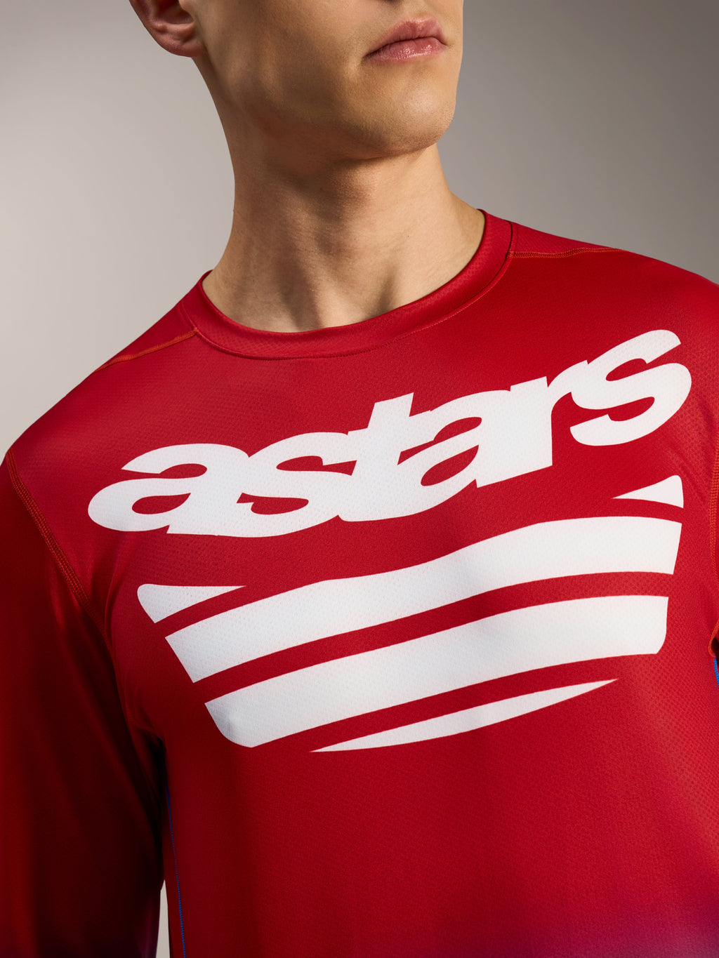 Maillot Alpinestars A-Dura ASTARS 2.0 rouge vif à manches longues, logo blanc et rayures sur la poitrine.