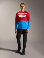 Maillot de VTT A-Dura ASTARS 2.0 à manches longues, dégradé rouge et bleu avec logos blancs, porté avec un pantalon noir.