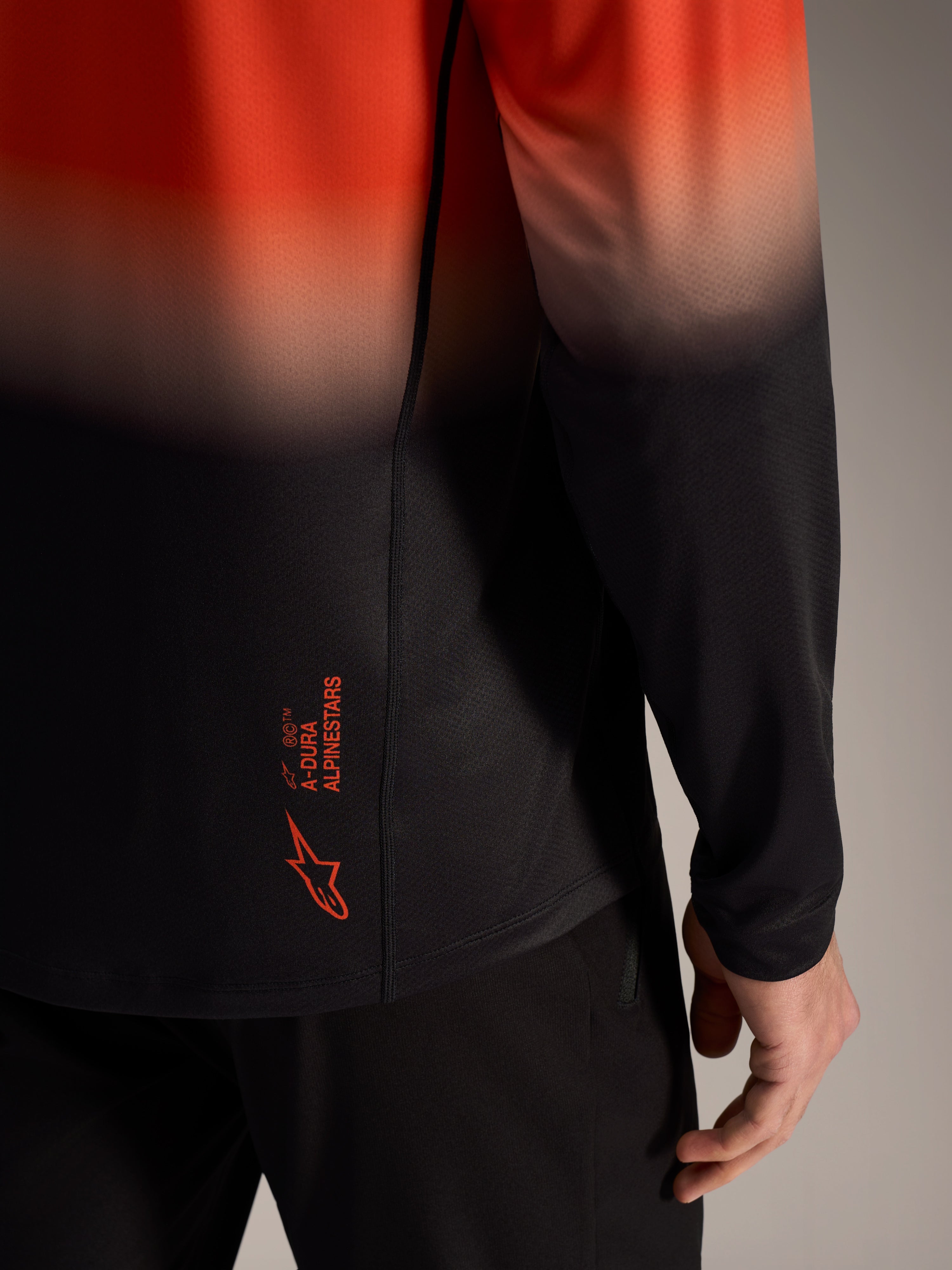 Maillot A-Dura ASTARS 2.0, dégradé orange et noir, logo au bas du dos et maille jacquard respirante.