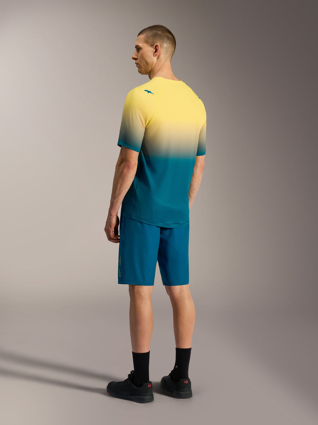 Maillot VTT A-Dura ASTARS 2.0 à manches courtes, dégradé jaune et bleu, avec short de performance bleu assorti.