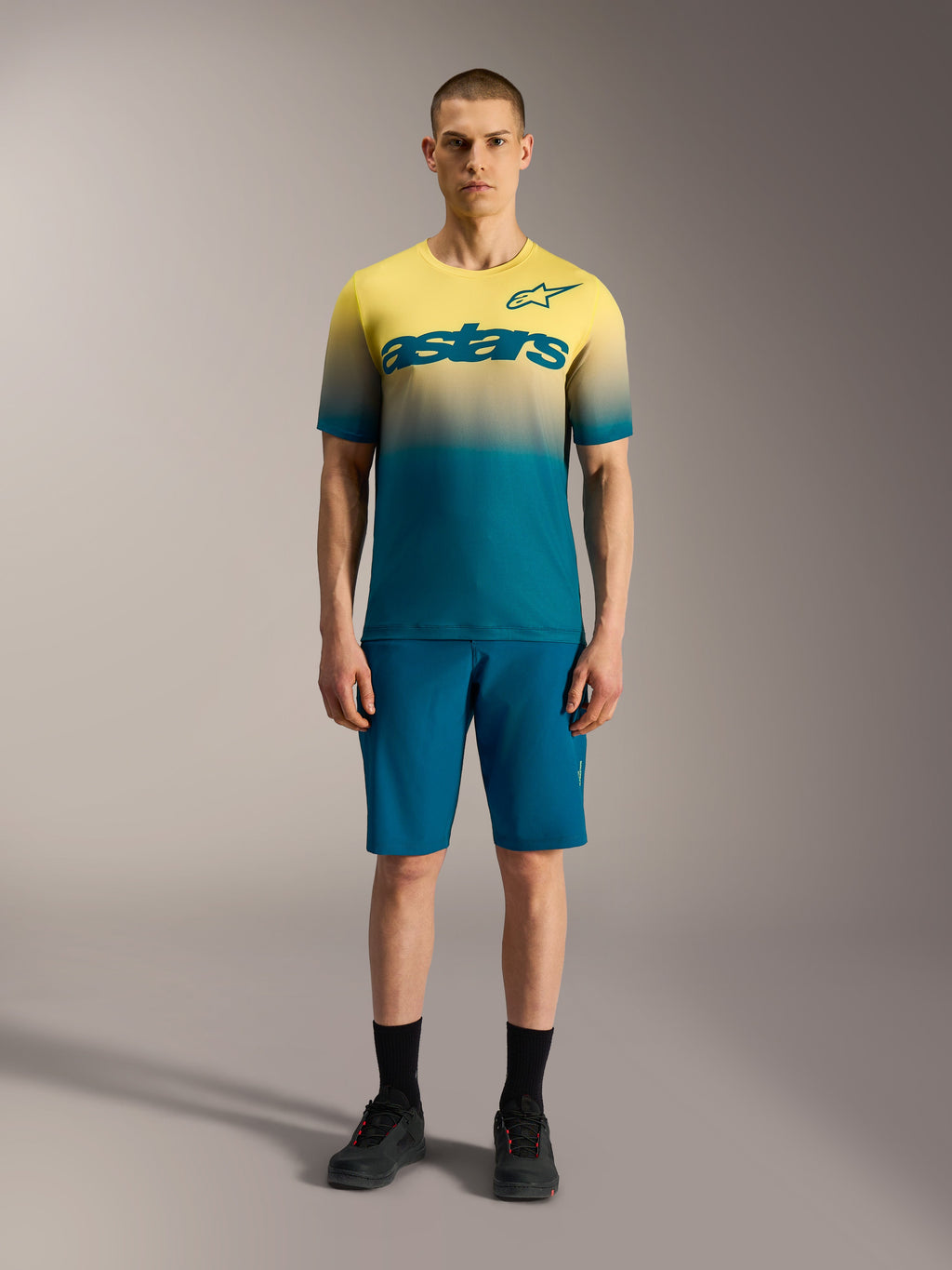 Maillot VTT Alpinestars A-Dura ASTARS 2.0 à manches courtes, dégradé jaune et bleu avec logo graphique sur le buste.