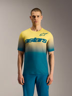 Maillot VTT A-Dura ASTARS 2.0 à manches courtes, dégradé bleu-vert à jaune fluo avec logo Astars sur la poitrine.