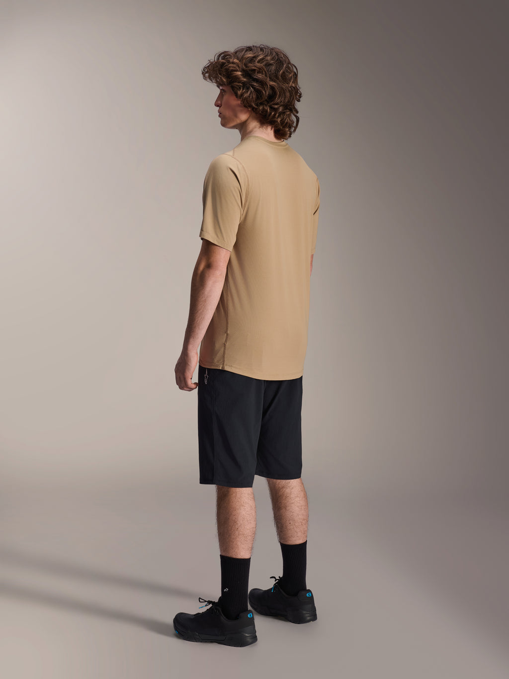Alpinestars A-Dura Shorts, Mountain Bike Shorts, Black, paired with a tan A-Dura short-sleeve jersey and black riding shoes, featuring a regular fit and durable construction for off-road cycling, rear-side view