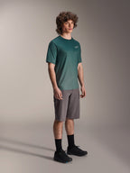 Alpinestars A-Dura Rise Jersey - Short Sleeve en Silver Pine, maillot de VTT vert porté par un mannequin avec un short gris et des baskets noires, tenue de VTT décontractée avec un petit logo blanc sur la poitrine