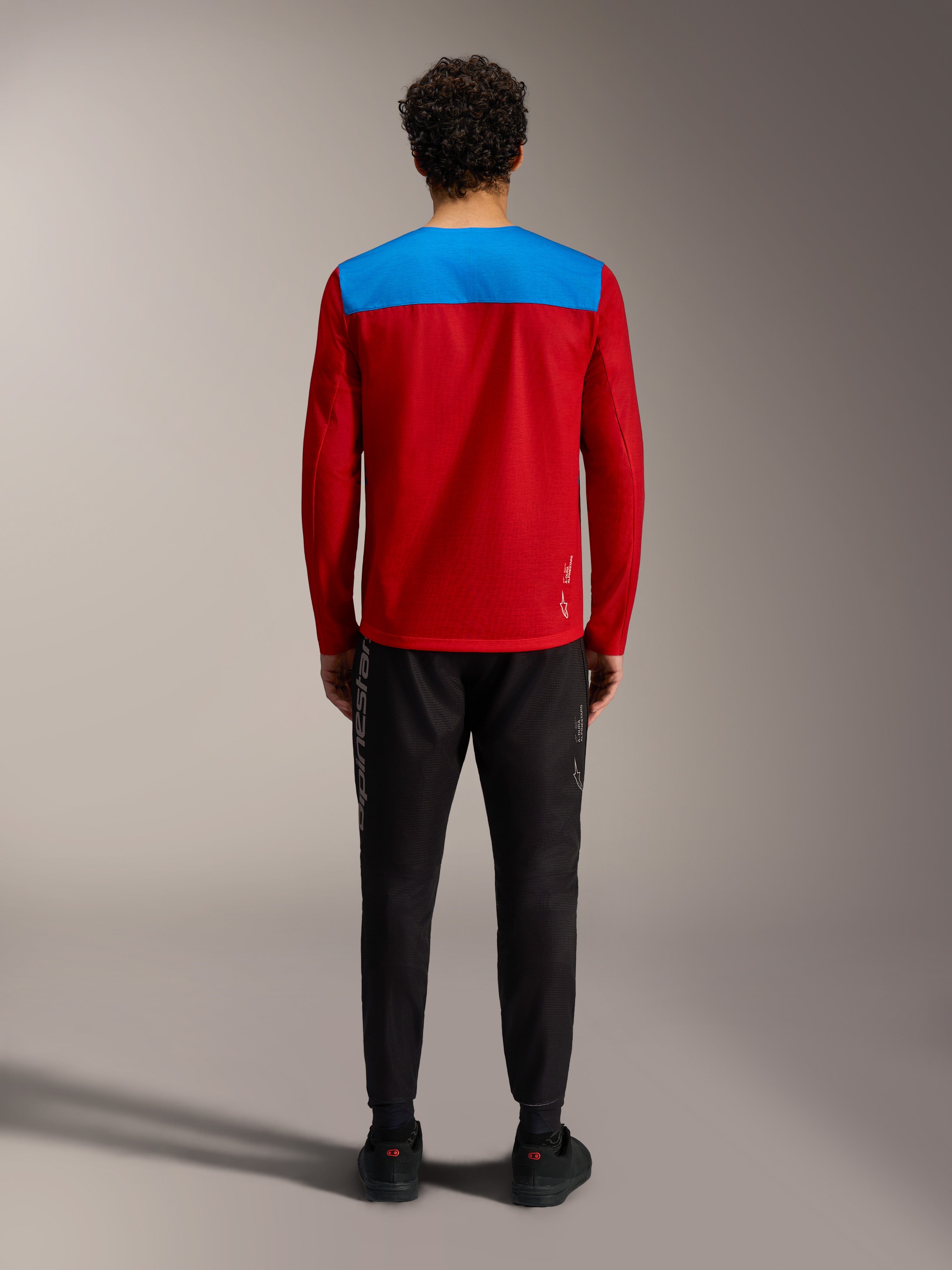 Maillot VTT Alpinestars A-Dura Elite 2.0 rouge et bleu, vue de dos avec un pantalon technique noir.