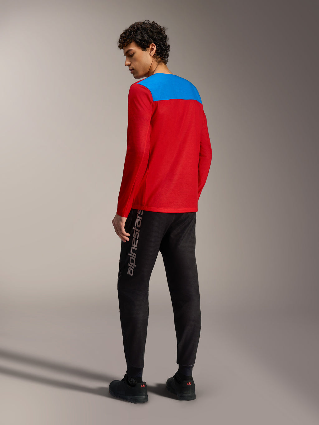 Maillot VTT Alpinestars A-Dura Elite 2.0 rouge à manches longues, empiècement dorsal bleu et pantalon technique noir.