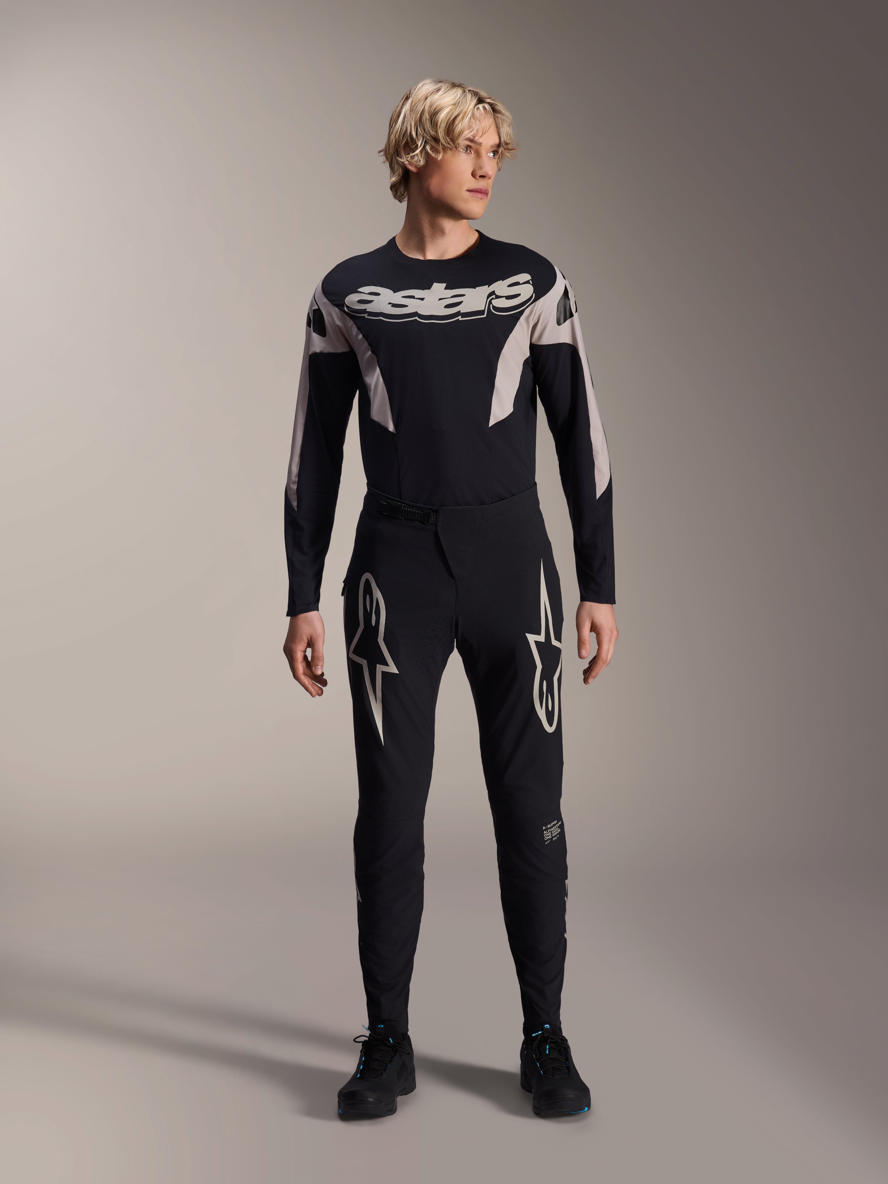 Maillot Alpinestars A-Supra Melt, maillot de VTT à manches longues, noir avec marquage Astars blanc sur la poitrine, porté avec un pantalon de VTT noir assorti orné de logos en étoile, équipement de cyclisme haute performance