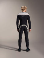 Homme vu de dos portant le maillot à manches longues Alpinestars A-Supra Melt noir avec empiècement gris clair aux épaules, associé à un pantalon de VTT noir arborant un large logo Alpinestars à l'arrière, tenue de VTT haute performance