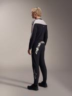 Pantalon Alpinestars A-Supra Melt, pantalon de VTT, noir, avec un grand logo Alpinestars blanc sur l'empiècement arrière et le logo étoile sur la jambe, porté par un mannequin avec un maillot à manches longues assorti et des chaussures noires, vue de dos
