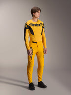 Modèle portant le maillot Alpinestars Limited Edition A-Supra Melt Gold, maillot de VTT à manches longues jaune foncé et noir, avec pantalon jaune assorti et chaussures noires, équipement technique de cyclisme tout-terrain aux graphismes inspirés de la course