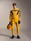 Mannequin portant l'ensemble Alpinestars Limited Edition A-Supra Melt Gold, maillot jaune foncé à manches longues avec logo Astars noir, pantalon jaune assorti avec détails noirs, tenant un casque jaune et noir, gants noirs et chaussures techniques, tenue de course de VTT