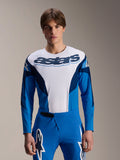 Maillot à manches longues Alpinestars A-Supra Melt, maillot de VTT bleu et blanc, logo astars imposant sur la poitrine, manches bleu foncé, porté avec un pantalon de course bleu assorti avec logos étoiles blancs, équipement de VTT haute performance