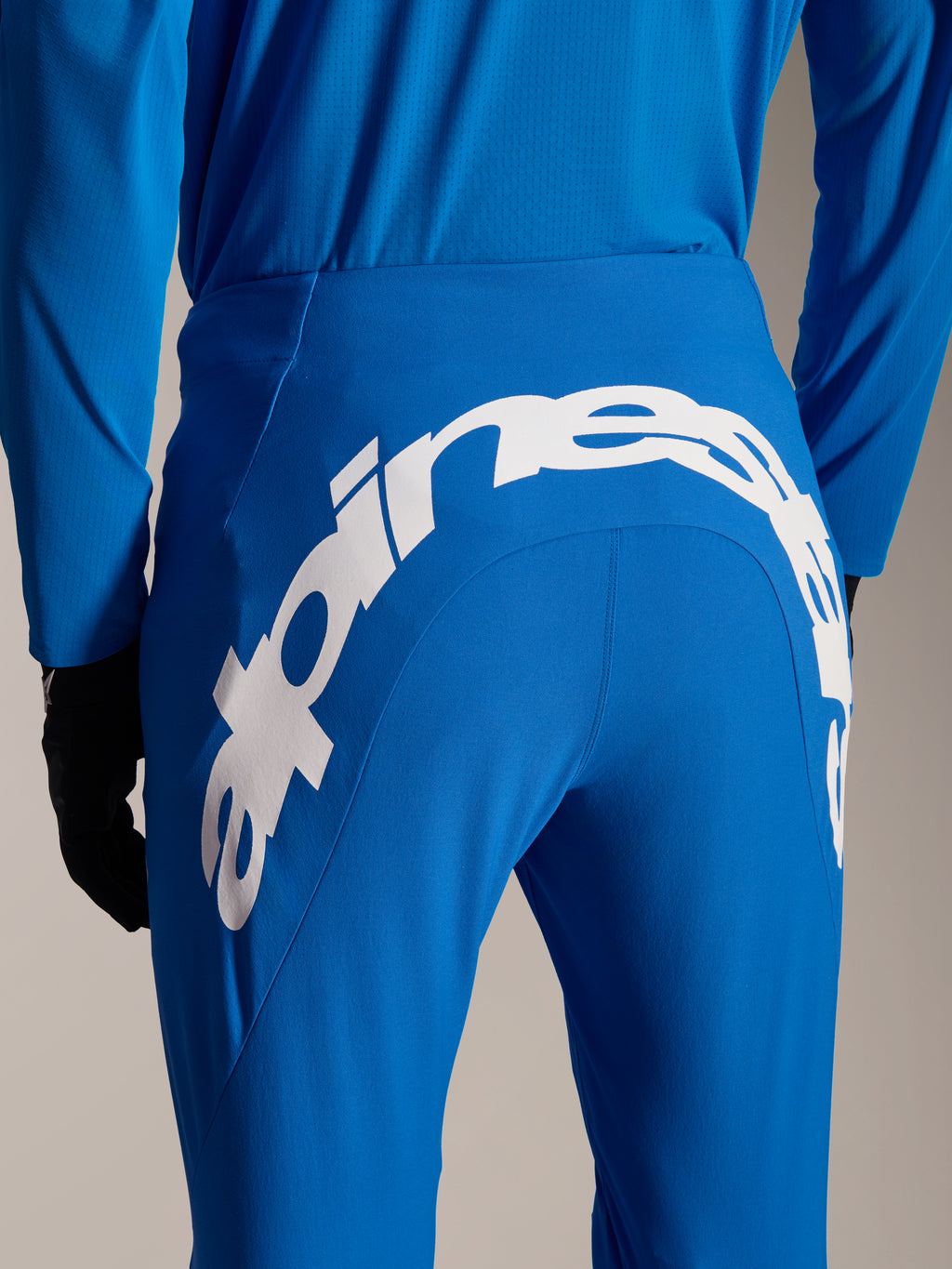 Pantalon et maillot Alpinestars A-Supra Melt, équipement VTT bleu, vue arrière avec grand logo Alpinestars blanc sur l'empiècement arrière du pantalon, maillot à manches longues et gants noirs assortis
