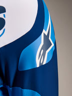 Maillot Alpinestars A-Supra Melt, maillot de VTT à manches longues bleu, gros plan sur la manche montrant le logo graphique ASTARS et le tissu micro-perforé pour la ventilation