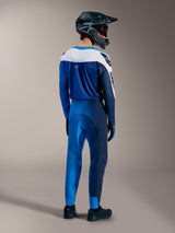 Ensemble VTT A-Supra Elite en Faded Bright Blue, maillot et pantalon Alpinestars vus de dos avec casque intégral.