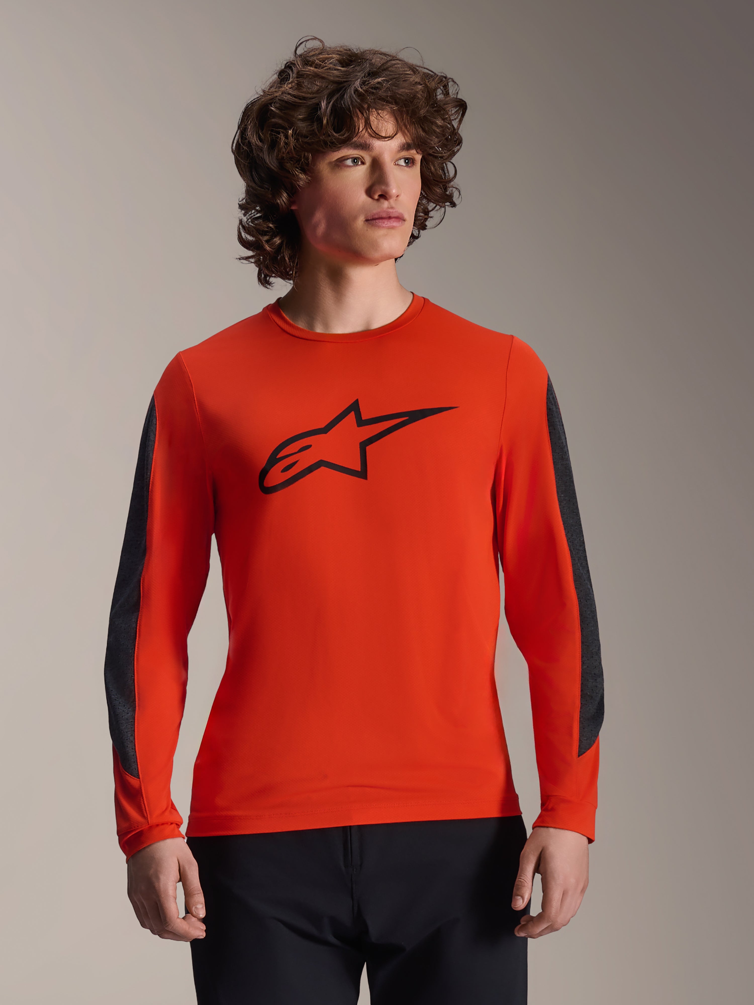 Maillot à manches longues Alpinestars A-Dura Insert Astar, orange avec logo Astar noir, empiècements de manches gris foncé résistants, porté par un mannequin homme, vêtement de cyclisme VTT haute performance