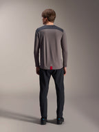 Maillot à manches longues Alpinestars A-Dura Insert Astar en gris foncé, vue de dos, doté d'empiècements anthracite aux épaules et d'une étiquette rouge à l'ourlet, porté avec un pantalon et des chaussures noirs, vêtement de performance pour le VTT