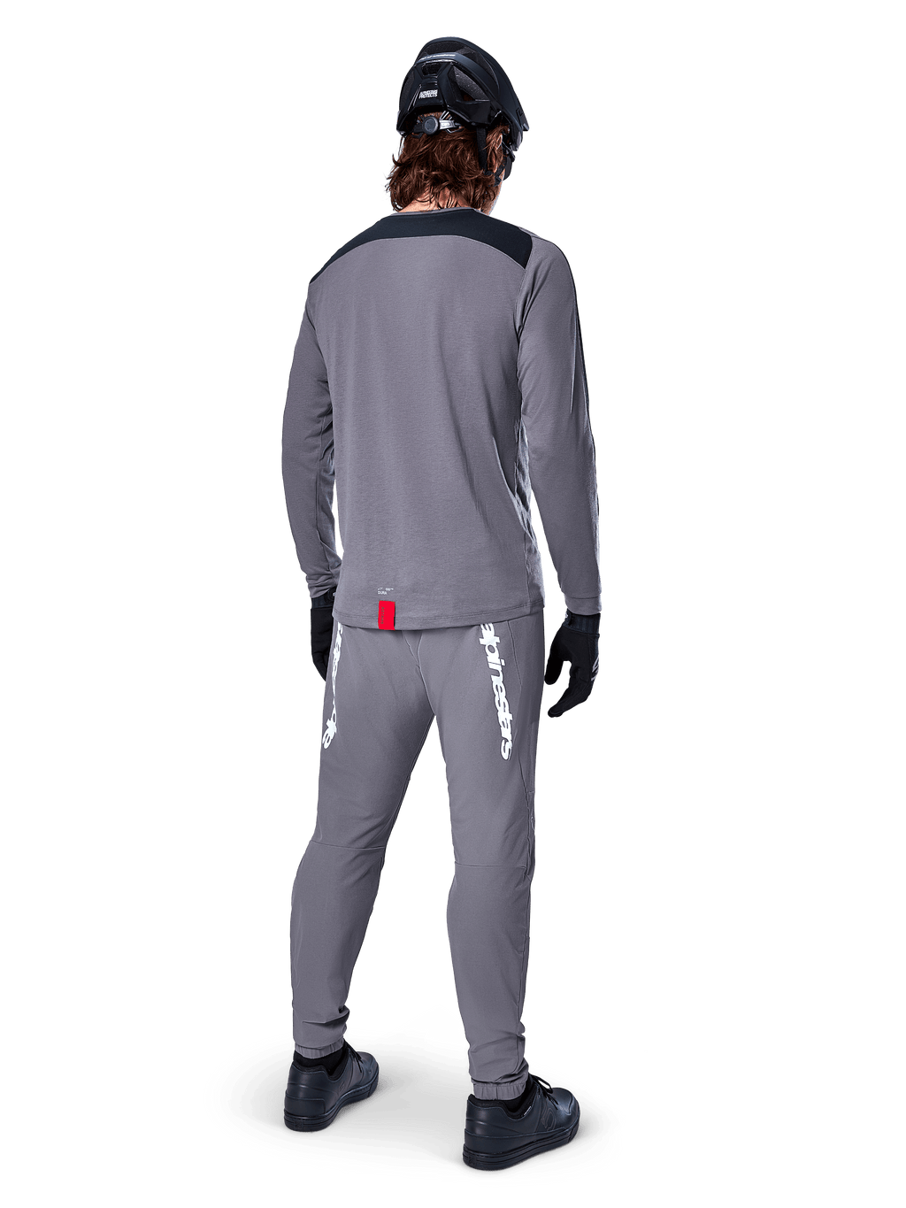 Alpinestars A-Dura Dri Astar Jersey - Long Sleeve, Dark Gray, back view of rider wearing matching pants and black helmet, features black shoulder panels and a small red tag at the hem, technical off-road cycling gear