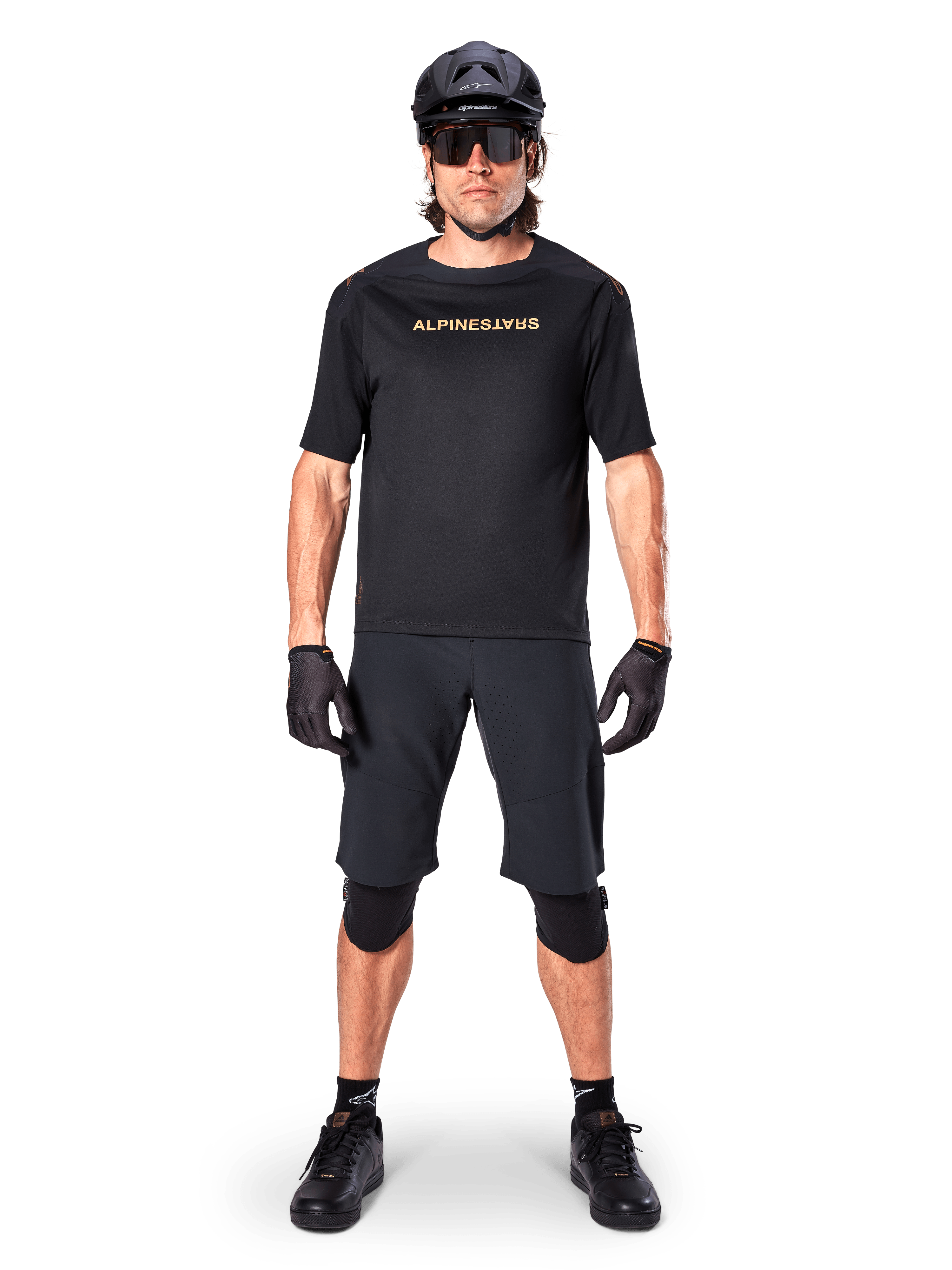 Alpinestars A-Aria Polartec Switch Jersey, Short Sleeve MTB Jersey, Black with tan lettering, worn with coordinated black mountain bike gear including helmet, shorts, and knee pads, performance off-road cycling apparel