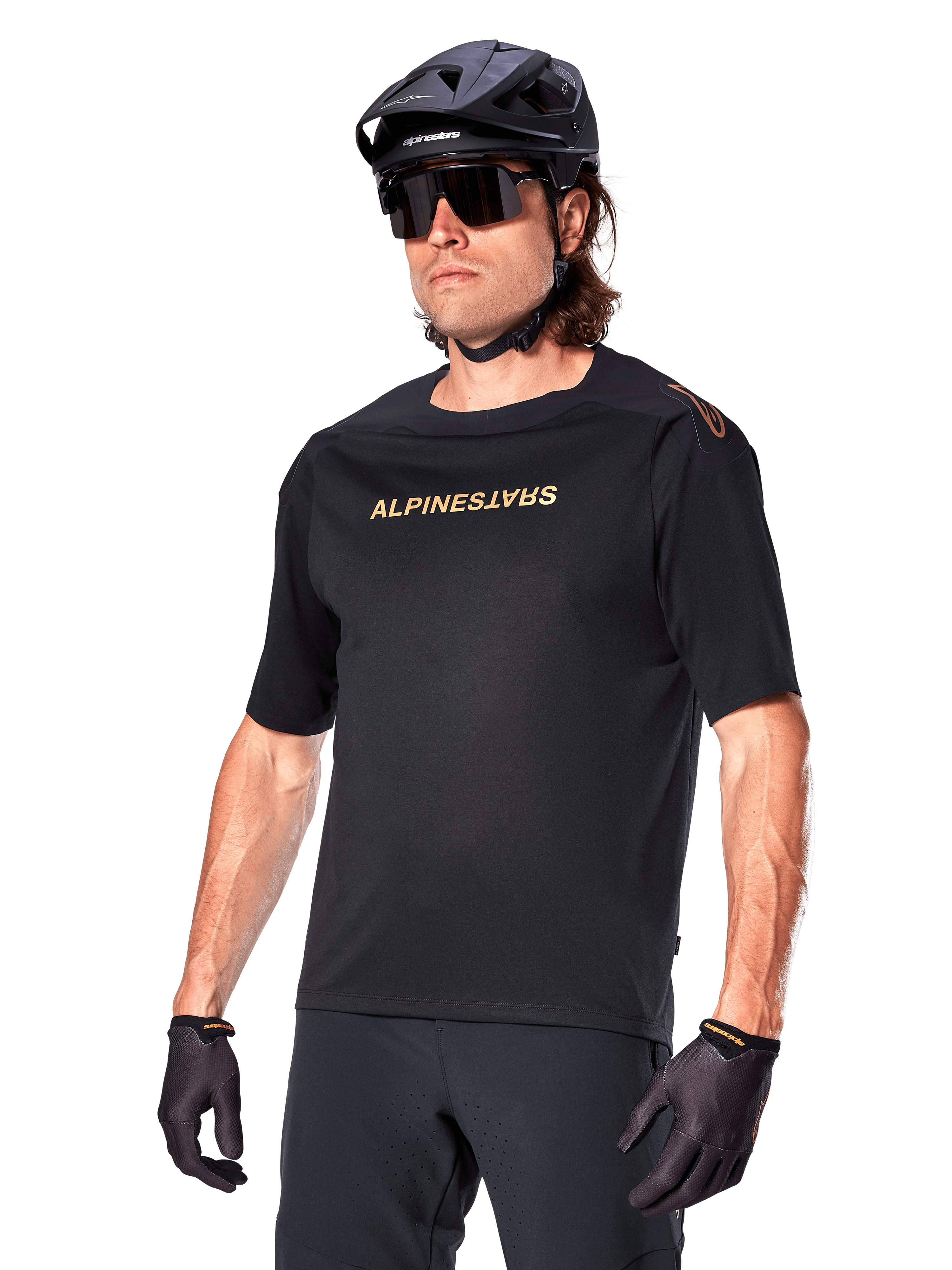 Alpinestars A-Aria Polartec Switch Jersey à manches courtes, maillot de VTT noir avec logo Alpinestars doré, porté avec un casque noir, des lunettes de soleil et des gants, équipement technique de VTT