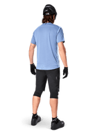 Alpinestars A-Dura Dri Astar Short Sleeve Jersey, Infinity Blue, rear view, paired with black mountain bike shorts and helmet, technical cycling apparel with moisture-wicking fabric and drop tail