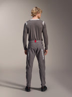 Modèle de dos portant le pantalon Alpinestars A-Dura Elite en gris foncé et un maillot à manches longues assorti, avec des logos Alpinestars blancs sur les jambes, un accent rouge à la taille et des chaussures noires, équipement de VTT professionnel.