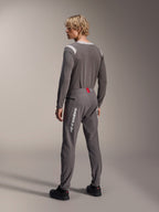 Modèle vu de dos portant un équipement de VTT Alpinestars, maillot à manches longues gris A-Dura Dri Wool, pantalon A-Dura Elite gris foncé avec marquage vertical blanc et détail rouge à la taille, tenue de cyclisme coordonnée pour le VTT