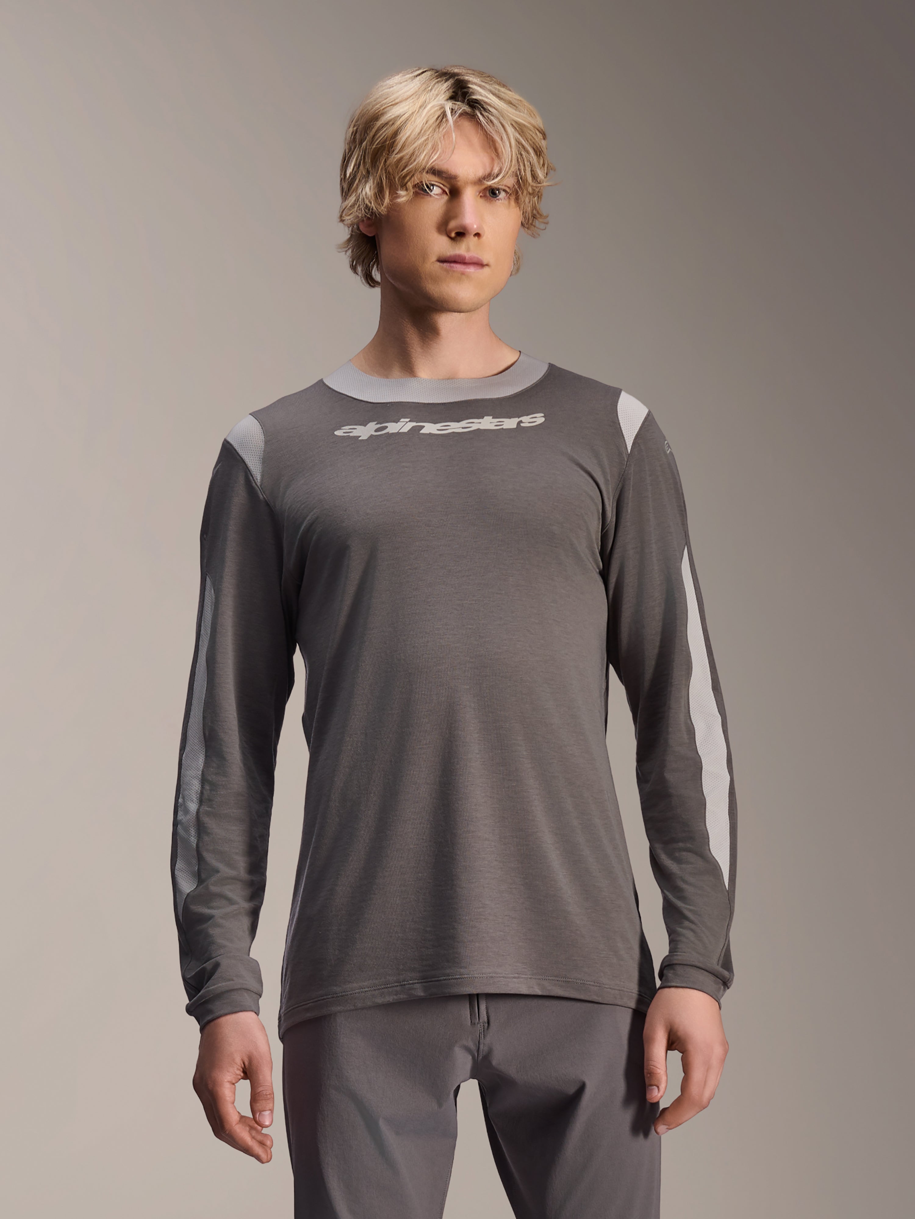 Maillot à manches longues Alpinestars A-Dura Dri Wool, gris foncé, porté par un mannequin homme, avec des panneaux en maille gris clair sur les épaules et les manches, logo textuel blanc sur la poitrine, équipement de performance pour VTT