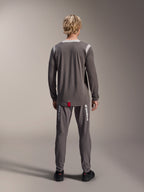 Maillot à manches longues Alpinestars A-Dura Dri Wool, gris foncé, vue de dos sur modèle, avec panneaux en maille gris clair sur les épaules et le col, pan arrière allongé avec une petite étiquette rouge, porté avec un pantalon de cyclisme gris assorti