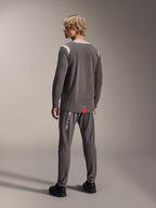 Mannequin homme portant le maillot à manches longues Alpinestars A-Dura Dri Wool, gris foncé avec empiècements en mesh gris clair aux épaules, associé à un pantalon de cyclisme gris foncé assorti, vue de dos montrant le pan arrière allongé, tenue de VTT