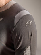 Maillot Alpinestars A-Dura Dri Wool - Manches Longues, Gris Foncé, vue détaillée de l'épaule et de la manche montrant les panneaux de ventilation en maille gris clair et le logo Astars blanc sur le tissu technique drirelease.