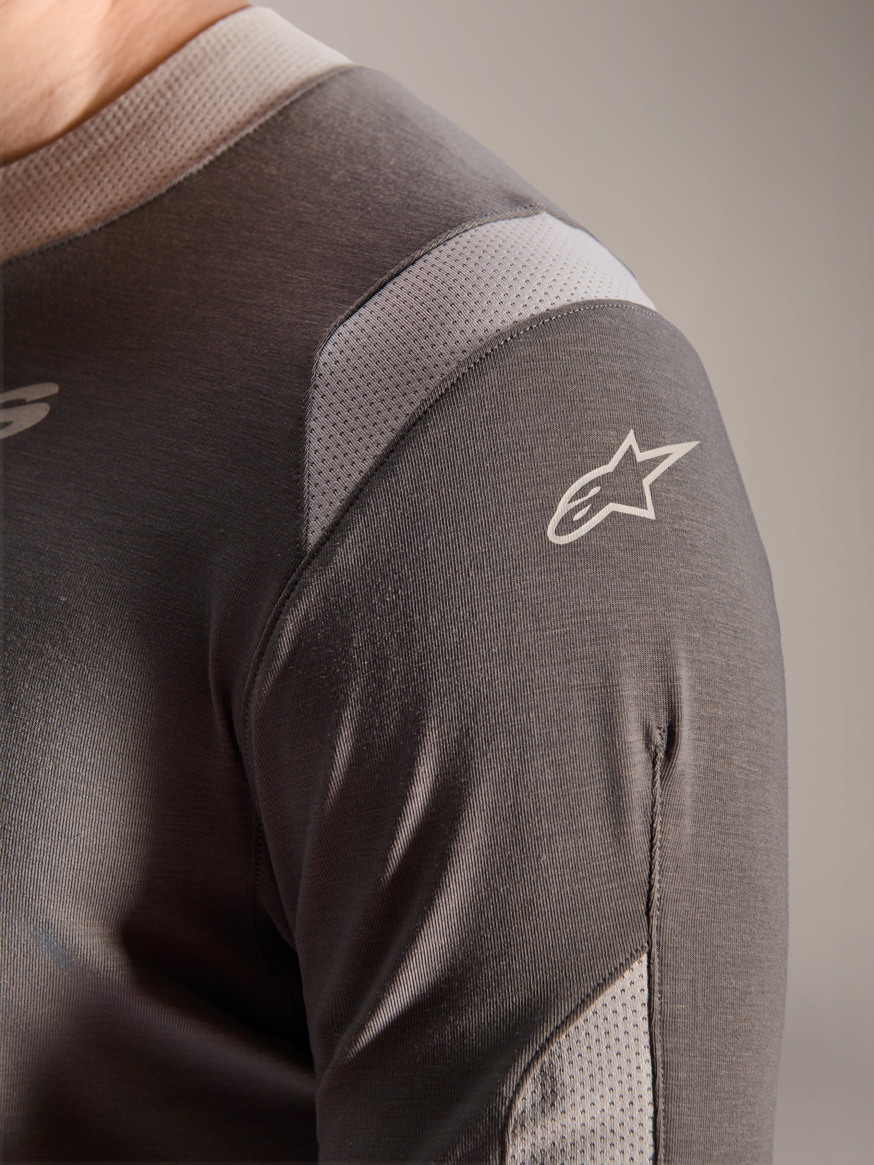 Maillot Alpinestars A-Dura Dri Wool - Manches Longues, Gris Foncé, vue détaillée de l'épaule et de la manche montrant les panneaux de ventilation en maille gris clair et le logo Astars blanc sur le tissu technique drirelease.