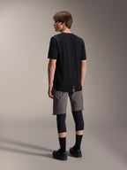 Alpinestars A-Dura Dri Wool Short Sleeve Jersey, Black, back view on model, worn with grey mountain biking shorts and black knee guards, featuring a dropped tail hem and subtle logo, technical MTB apparel
