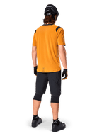 Alpinestars A-Dura Dri Wool Short Sleeve Jersey, Cycling Jersey, Dark Gold, back view of mountain biker wearing mustard-yellow jersey with black mesh shoulder accents, paired with black shorts, knee guards, black helmet, and gloves, technical off-road cycling gear