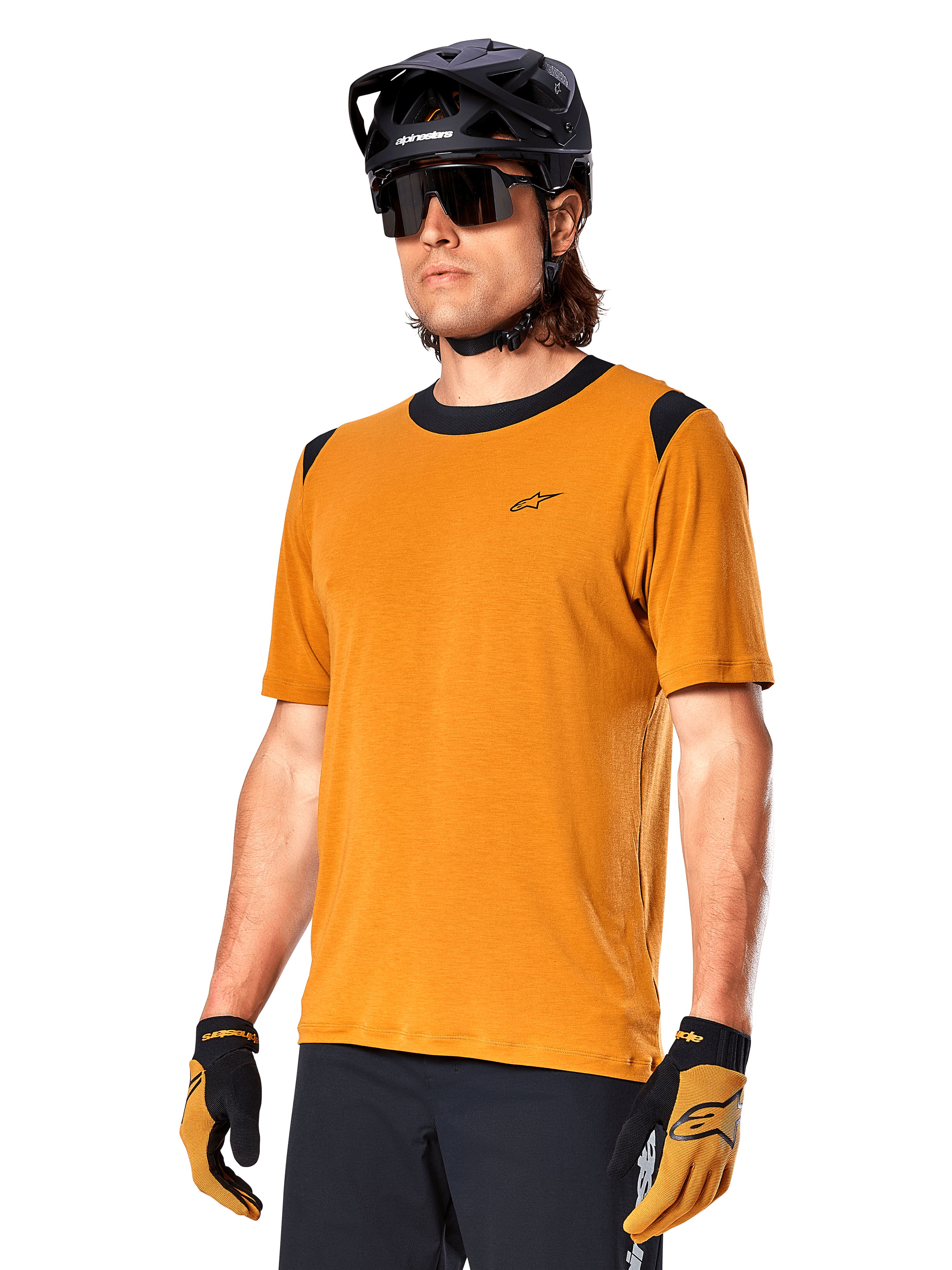 Maillot Alpinestars A-Dura Dri Wool à manches courtes, maillot de cyclisme VTT, Or foncé avec accents noirs, maillot technique à manches courtes en mélange de laine avec empiècements noirs aux épaules, porté avec un casque de VTT noir et des gants assortis