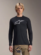 Maillot à manches longues Alpinestars A-Dura Astar, noir avec logo Astars argenté sur la poitrine, porté par un mannequin avec un pantalon camouflage, vêtement de performance VTT décontracté pour le vélo de montagne