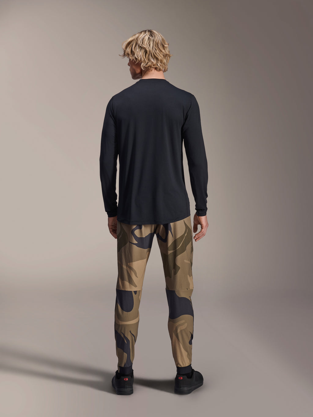 Maillot Alpinestars A-Dura Astar - Manches longues, noir, vue arrière d'un mannequin portant un pantalon camouflage, doté d'un pan arrière allongé et d'une coupe régulière pour le VTT