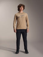 Maillot à manches longues Alpinestars A-Dura Astar, brun clair avec logo Astars gris sur la poitrine, porté par un mannequin avec un pantalon technique et des chaussures noirs, équipement de VTT décontracté et performant