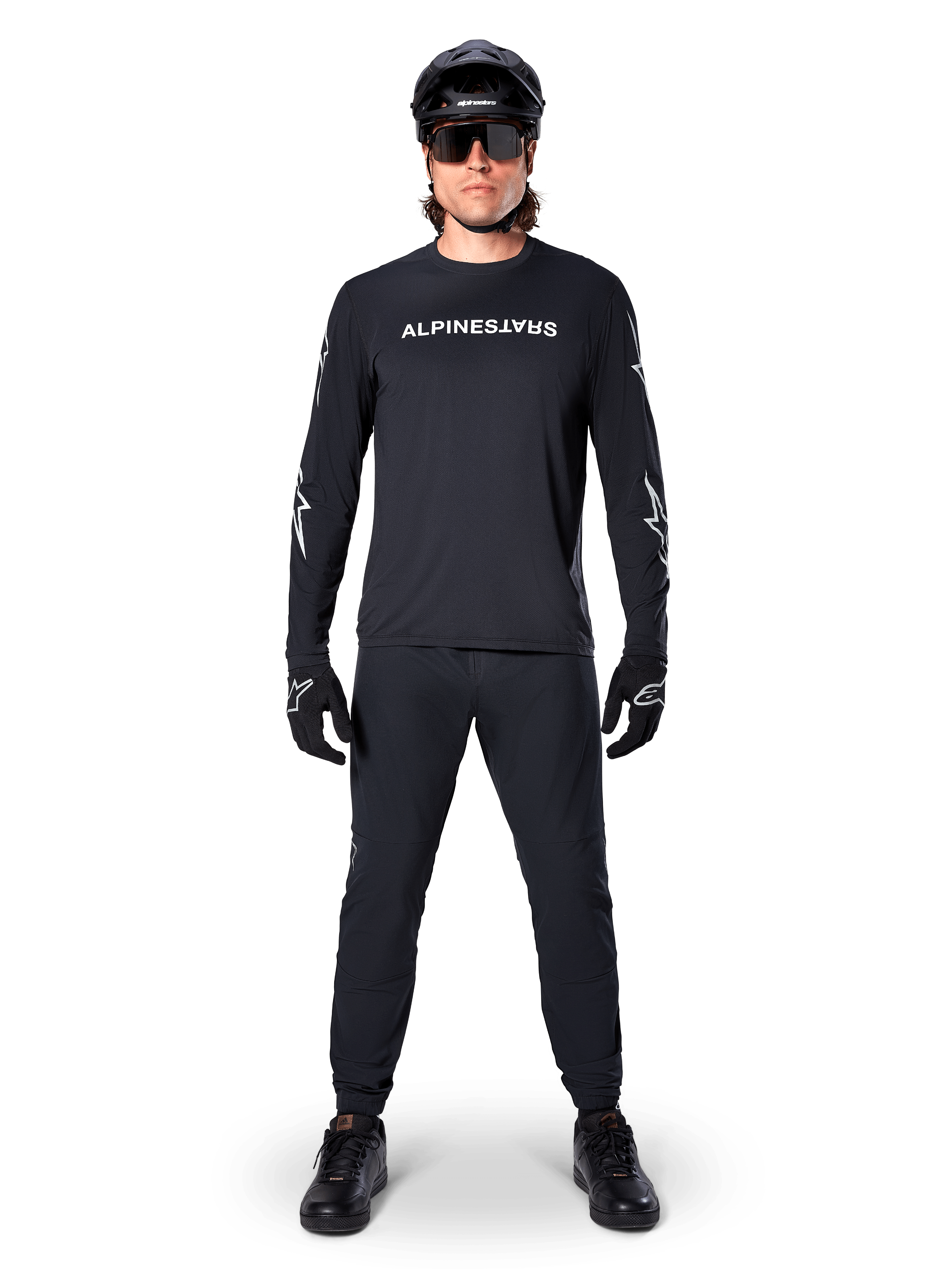 Alpinestars A-Dura Switch Long Sleeve Jersey, Black, worn by a mountain bike rider with matching black pants and helmet, featuring white wordmark logo on the chest, technical off-road cycling apparel