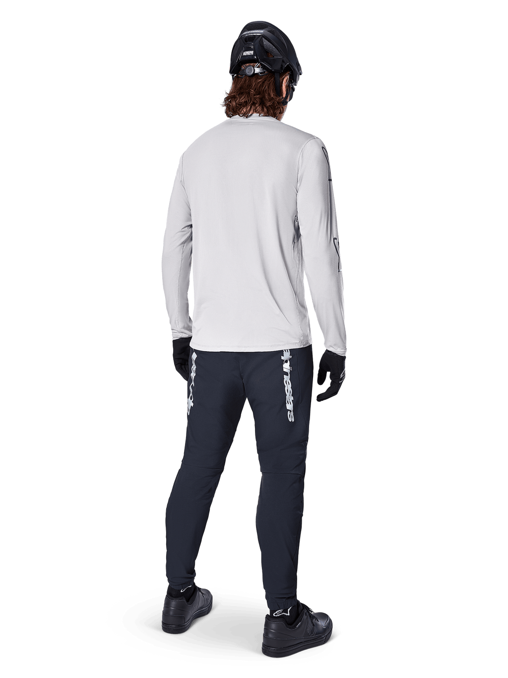 Maillot à manches longues Alpinestars A-Dura Switch, gris clair, vue arrière d'un cycliste portant un pantalon de cyclisme noir, un casque et des gants, équipement de VTT haute performance avec une queue plus longue.