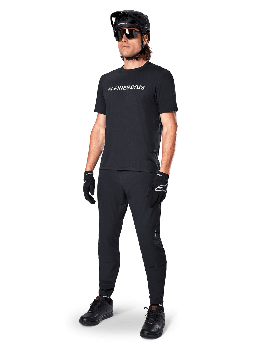 Maillot à manches courtes Alpinestars A-Dura Switch, noir, porté par un mannequin avec pantalon de VTT noir, casque et gants assortis, arborant le logo Alpinestars blanc sur la poitrine, vêtement de performance pour le VTT
