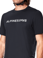 Maillot à manches courtes Alpinestars A-Dura Switch, noir, arborant un grand logo textuel blanc sérigraphié sur la poitrine, texture du tissu jacquard technique, vue de face en gros plan