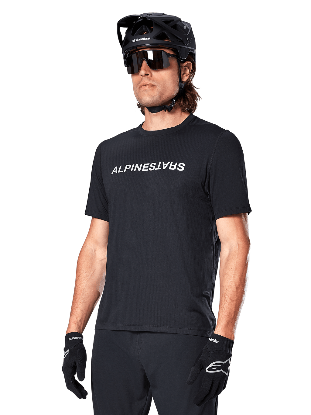 Maillot à manches courtes Alpinestars A-Dura Switch, noir, arborant un logo textuel blanc sur la poitrine, porté par un cycliste muni d'un casque de VTT noir et de lunettes de soleil, vêtement technique conçu pour le trail