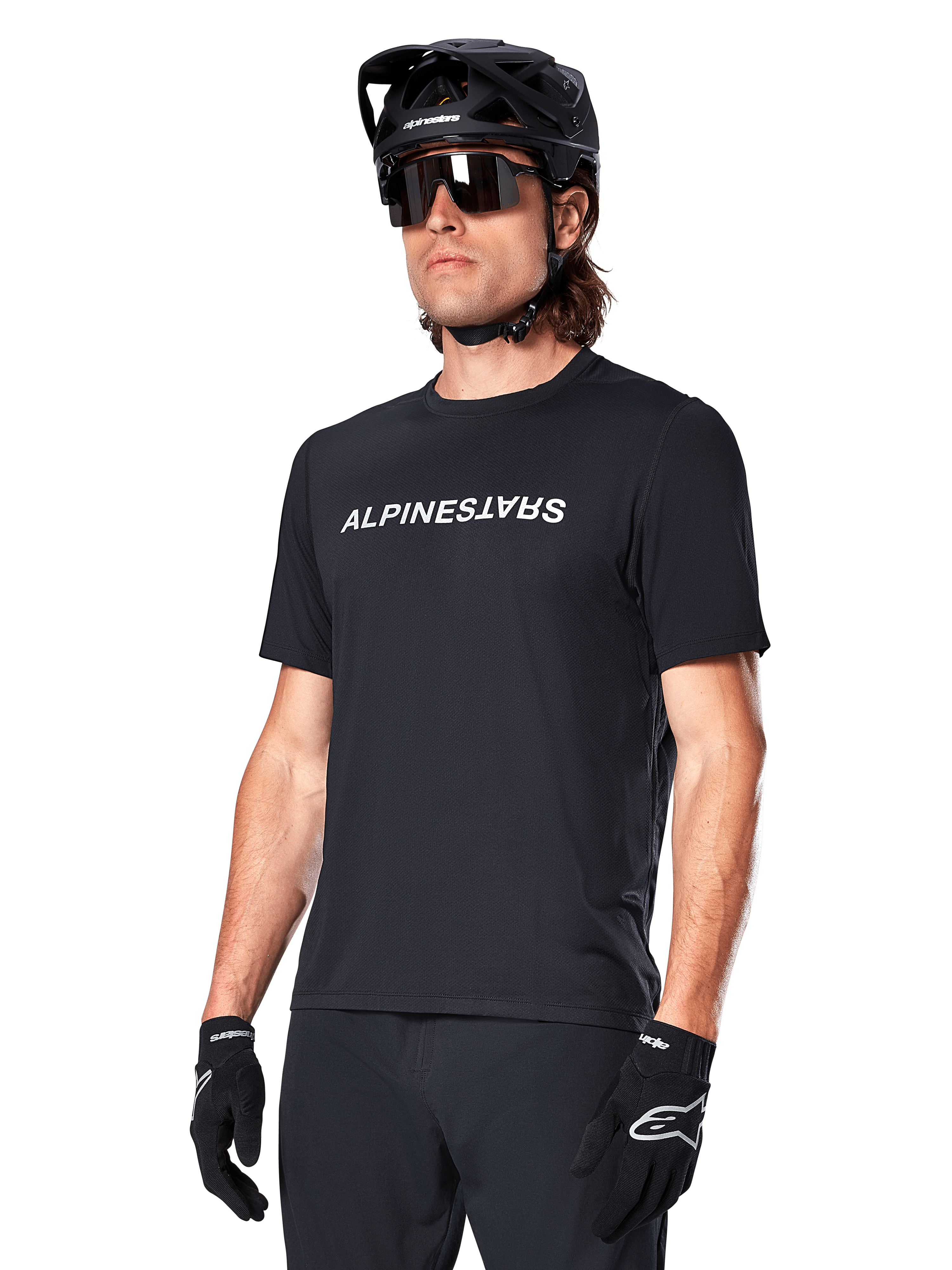 Maillot à manches courtes Alpinestars A-Dura Switch, noir, arborant un logo textuel blanc sur la poitrine, porté par un cycliste muni d'un casque de VTT noir et de lunettes de soleil, vêtement technique conçu pour le trail