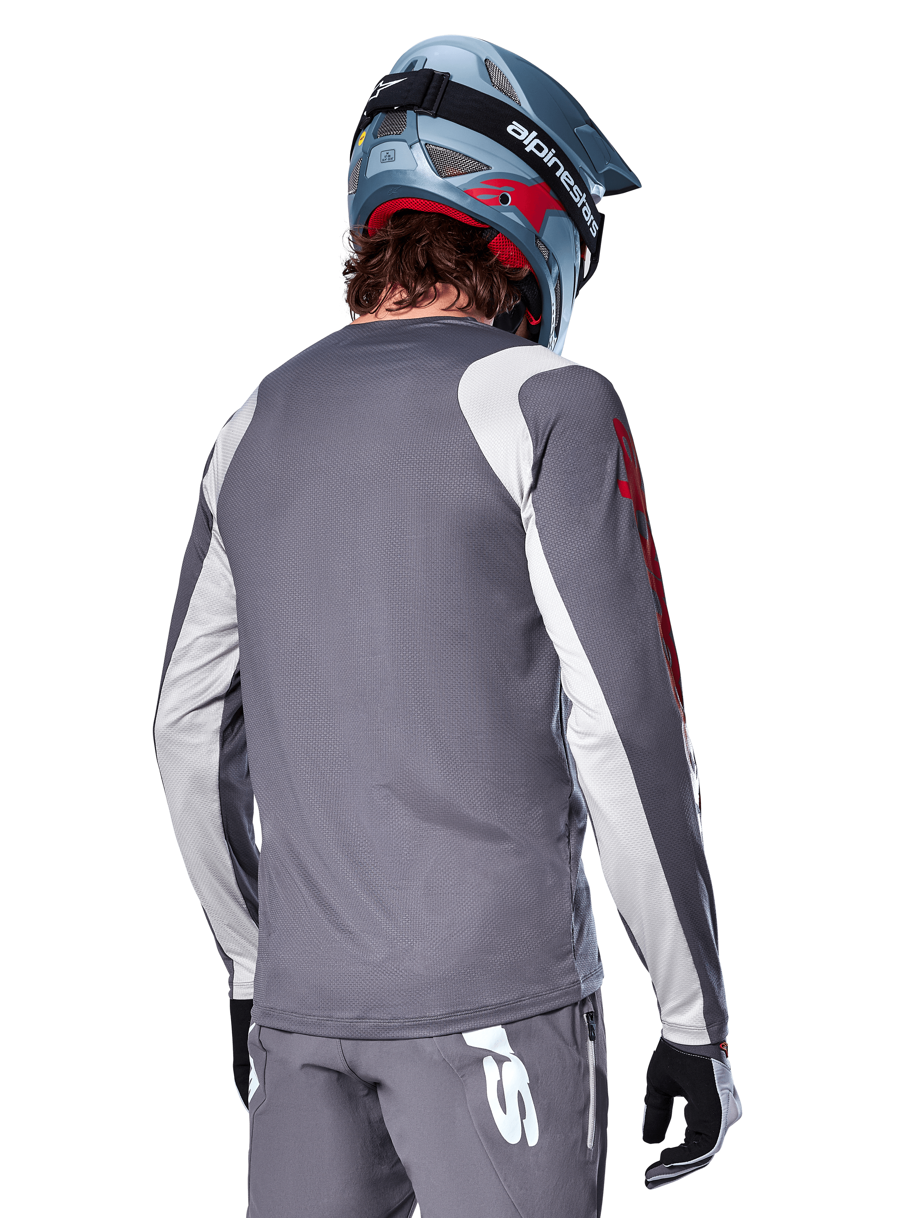 Maillot à manches longues Alpinestars A-Supra Astar, gris foncé avec empiècements gris clair aux épaules et aux bras, vue arrière d'un cycliste portant un casque de VTT intégral bleu et un pantalon gris, vêtement de cyclisme VTT haute performance