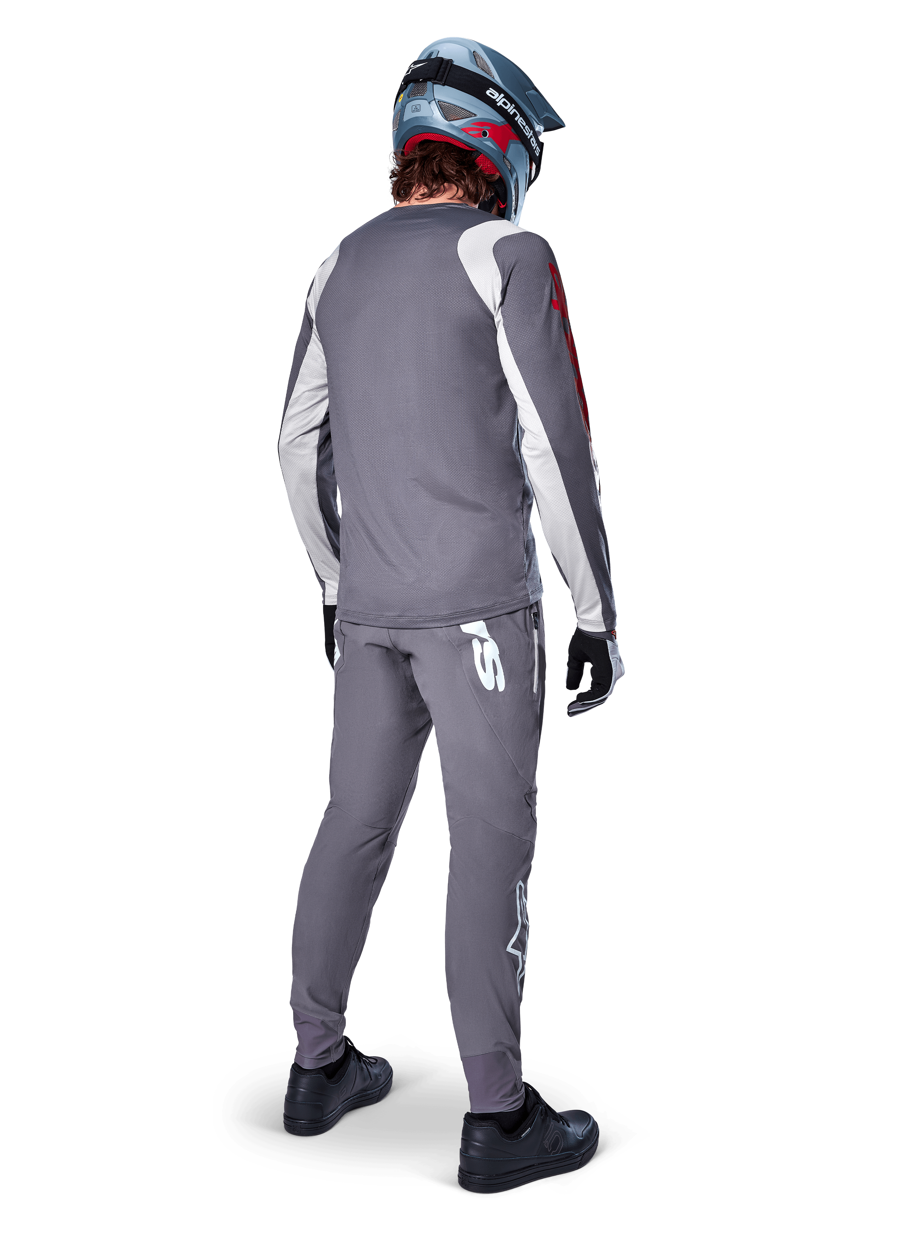 Maillot Alpinestars A-Supra Astar, maillot de VTT à manches longues, gris foncé avec accents blancs sur les manches et logo rouge, vue de dos d'un pilote portant un pantalon gris assorti et un casque intégral bleu, vêtements de cyclisme haute performance