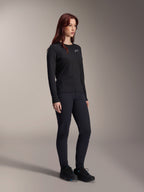 Femme portant le maillot thermique Alpinestars Stella A-Dura, maillot de VTT noir à manches longues avec logo blanc sur la poitrine, associé à un pantalon noir assorti et des chaussures de sport, portrait en studio pour vêtements de cyclisme de performance